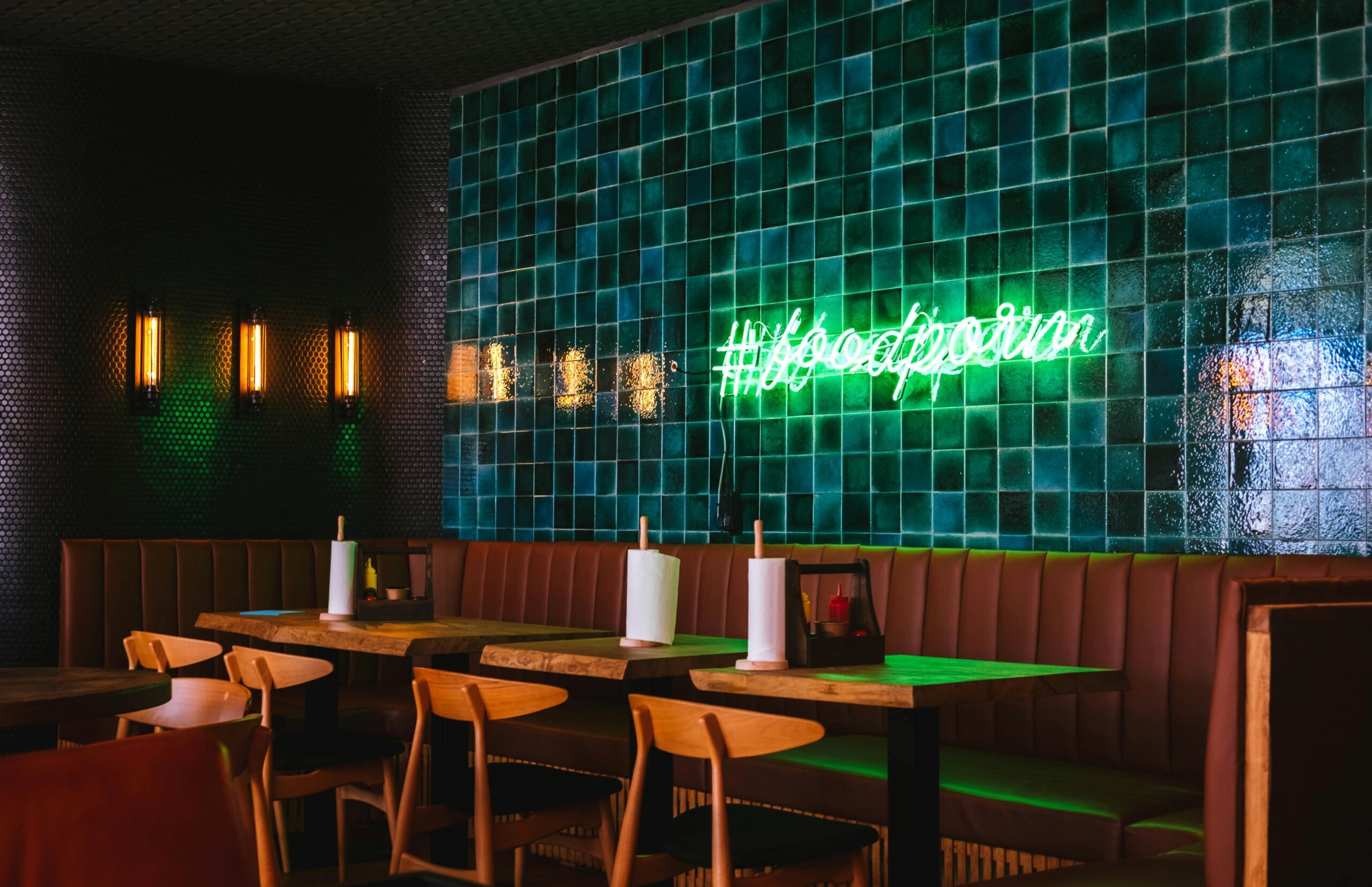 Contemporary restaurant interior with green tile wall and neon sign in Sochi, Russia.
